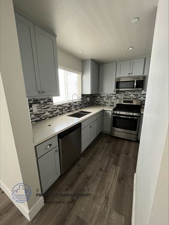 a kitchen with gray cabinets and a wooden floor